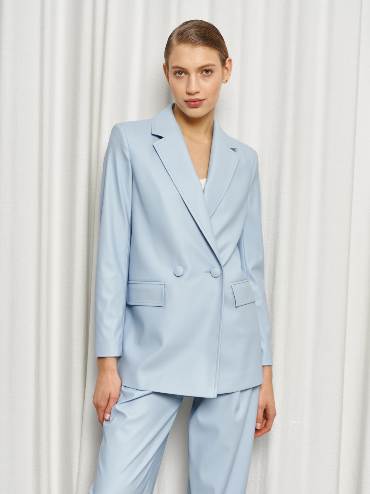 Жакет двубортного кроя выполнен из эко-кожи и оформлен заостренными лацканами, акцентированной плечевой линией и карманными клапанами по бокам.

На модели размер XS