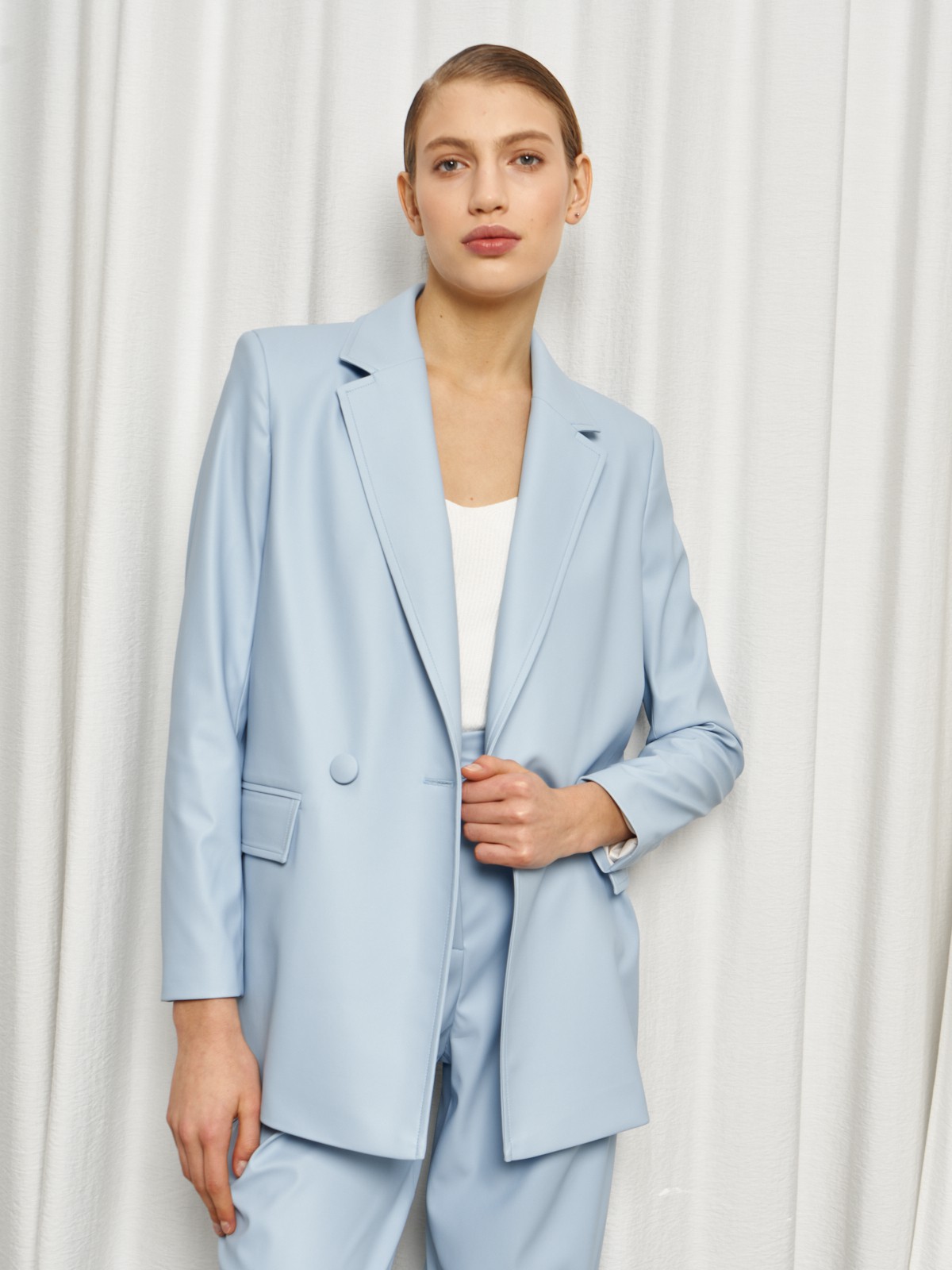 Жакет двубортного кроя выполнен из эко-кожи и оформлен заостренными лацканами, акцентированной плечевой линией и карманными клапанами по бокам.

На модели размер XS