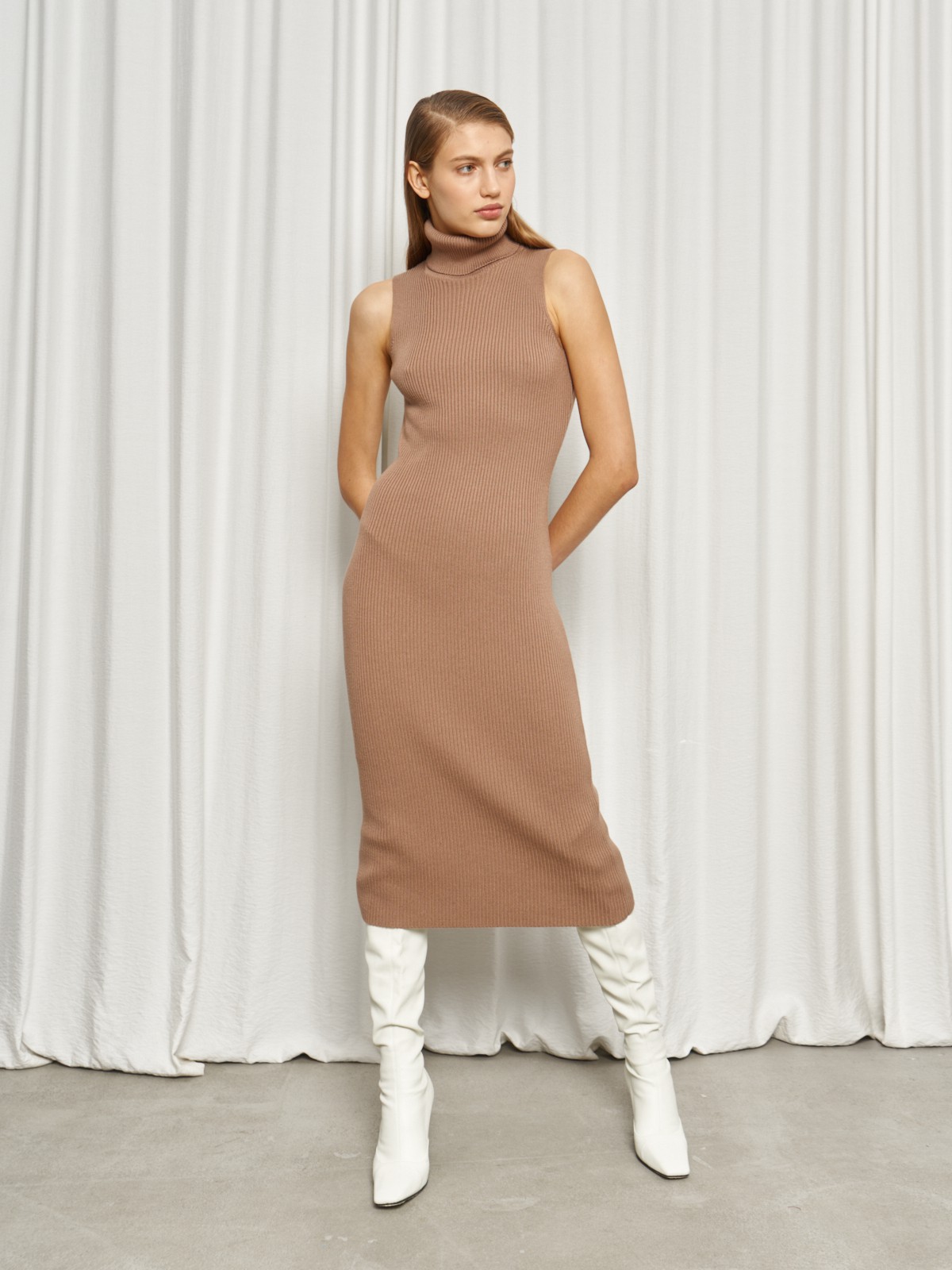 Платье без рукавов из вязаного трикотажа оформлено высокой горловиной-стойкой. Посадка по фигуре.

На модели размер XS