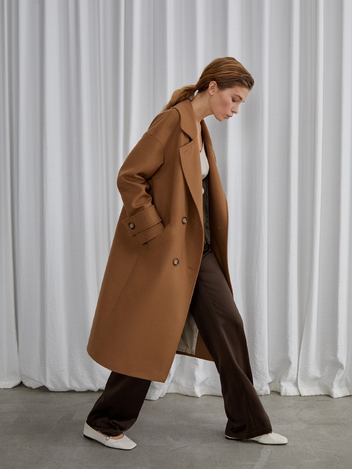 Пальто-кокон двубортного кроя с покатым рукавом и декоративными деталями: карманными клапанами, хлястиками на манжетах и лацканами у воротника.

На модели размер XS