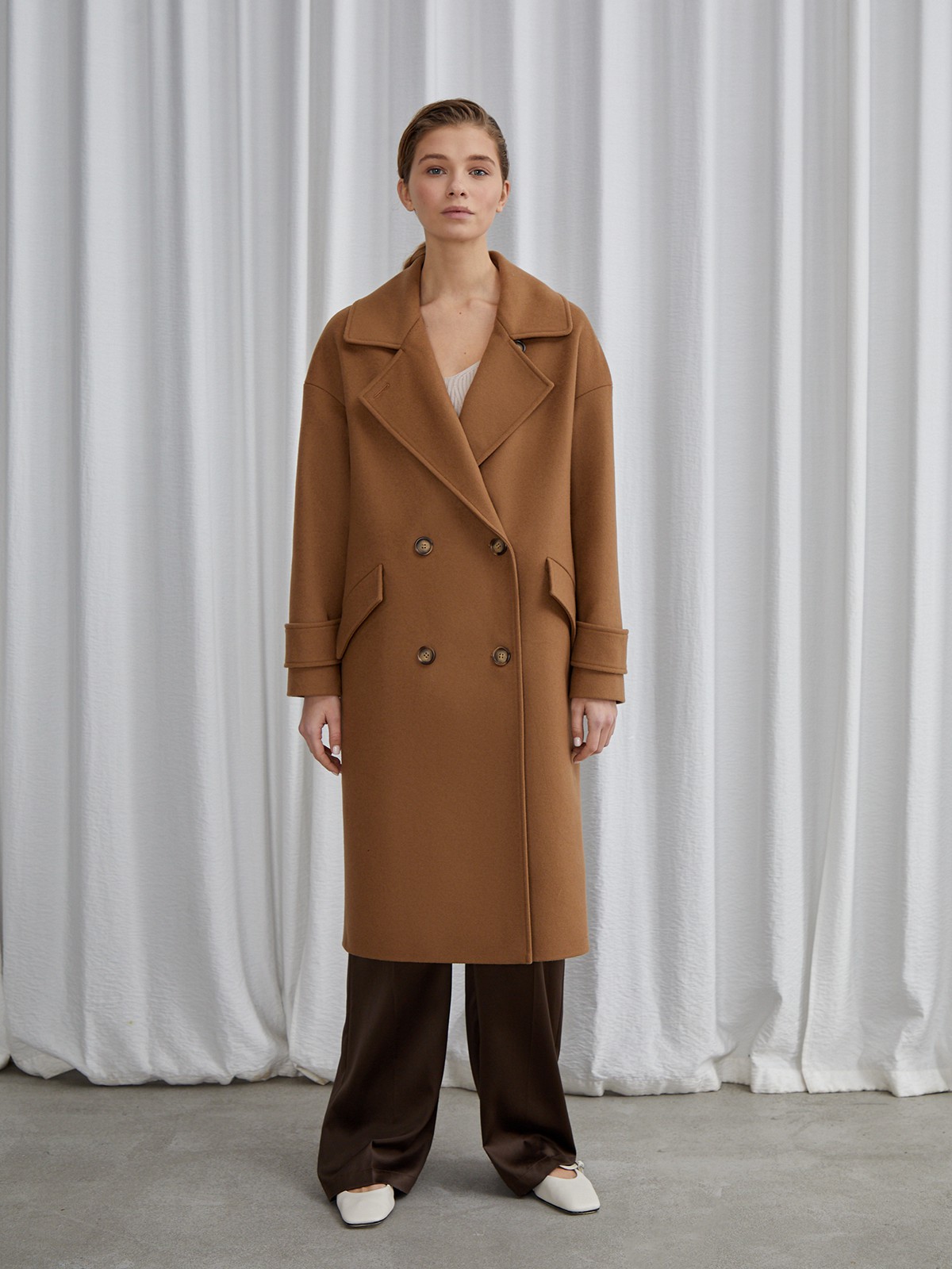 Пальто-кокон двубортного кроя с покатым рукавом и декоративными деталями: карманными клапанами, хлястиками на манжетах и лацканами у воротника.

На модели размер XS