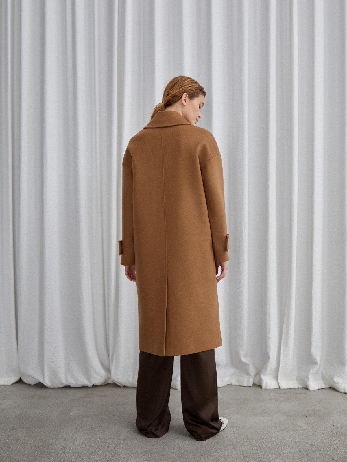 Пальто-кокон двубортного кроя с покатым рукавом и декоративными деталями: карманными клапанами, хлястиками на манжетах и лацканами у воротника.

На модели размер XS