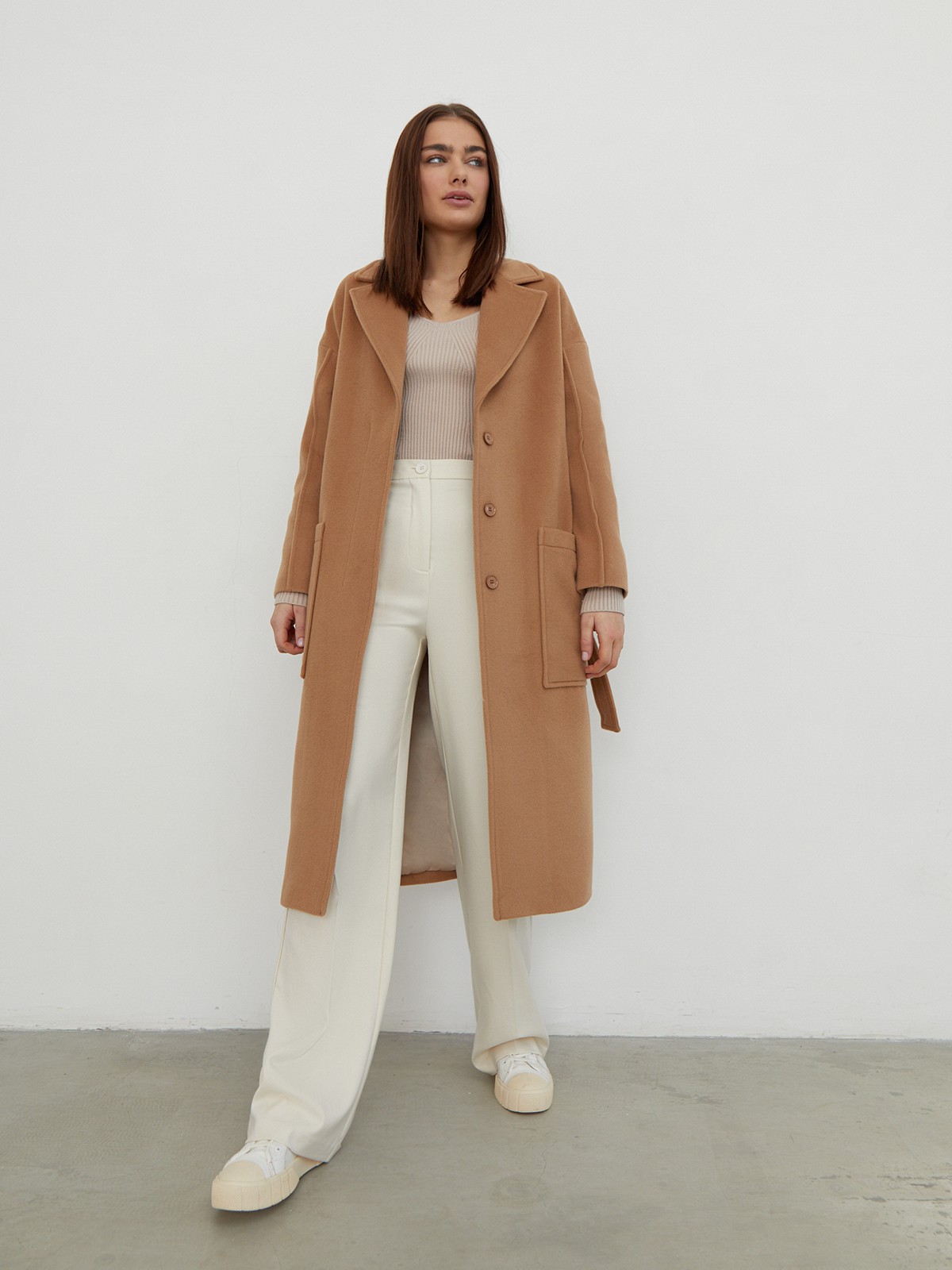 Пальто-халат однобортного кроя со спущенным рукавом и широкими лацканами. Глубокие накладные карманы по бокам, декоративная деталь на ремне.

На модели размер XS