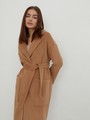 Пальто-халат однобортного кроя со спущенным рукавом и широкими лацканами. Глубокие накладные карманы по бокам, декоративная деталь на ремне.

На модели размер XS