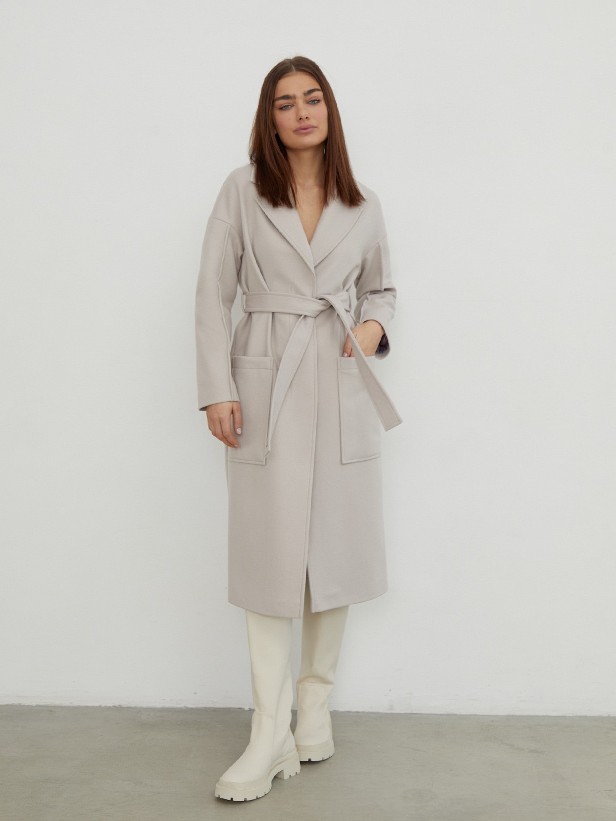 Пальто-халат однобортного кроя со спущенным рукавом и широкими лацканами. Глубокие накладные карманы по бокам, декоративная деталь на ремне.

На модели размер XS