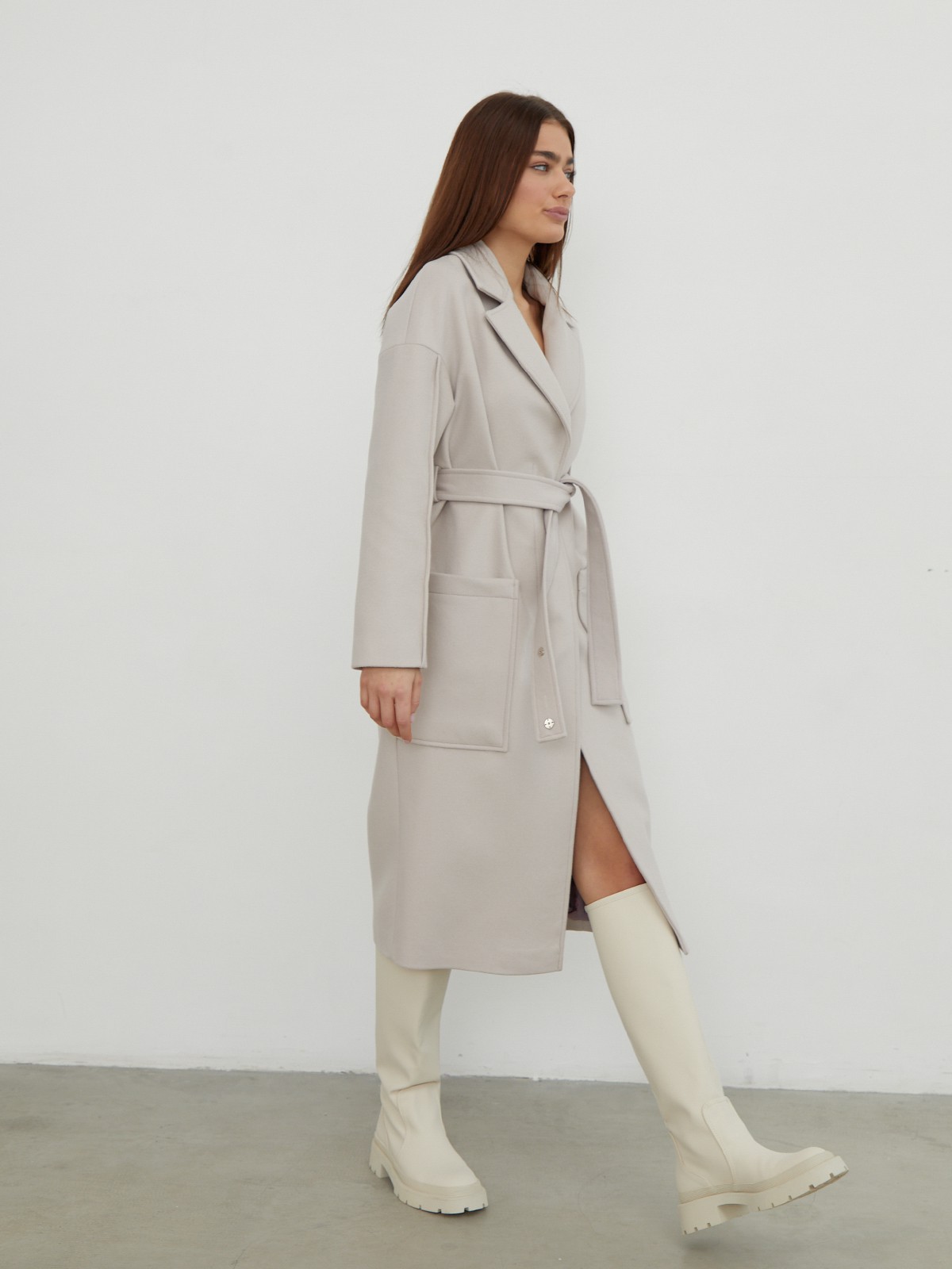 Пальто-халат однобортного кроя со спущенным рукавом и широкими лацканами. Глубокие накладные карманы по бокам, декоративная деталь на ремне.

На модели размер XS