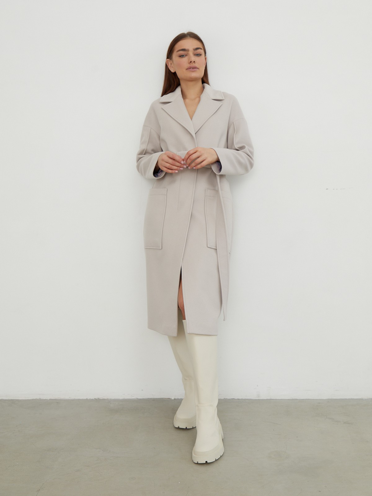 Пальто-халат однобортного кроя со спущенным рукавом и широкими лацканами. Глубокие накладные карманы по бокам, декоративная деталь на ремне.

На модели размер XS