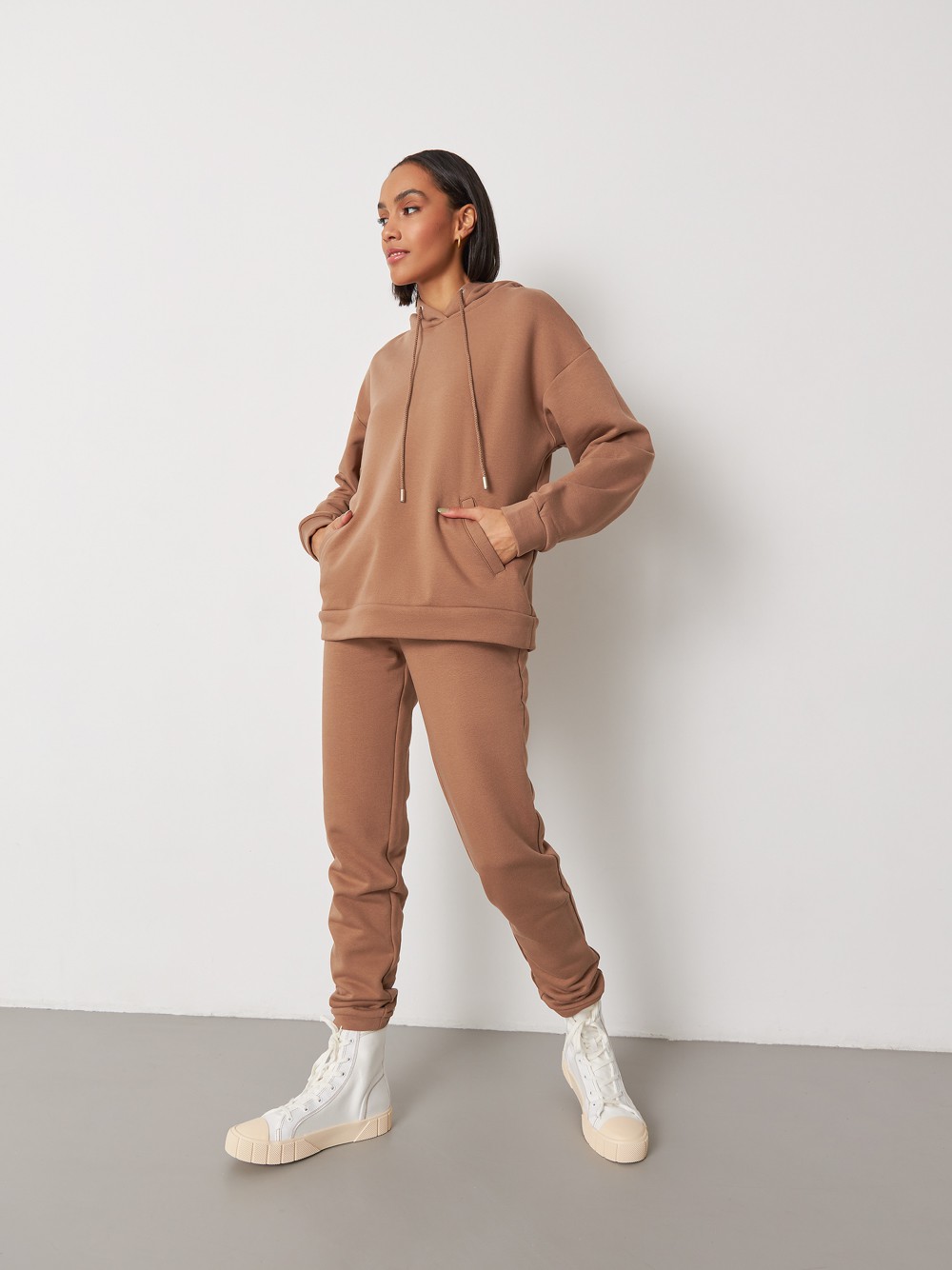 Брюки свободного спортивного силуэта. Модель дополнена манжетами из основной ткани по низу изделия и карманами по боковым швам. На поясе у брюк пояс, регулируемый завязками. Дополните свой образ толстовкой в тон изделия.

На модели размер XS