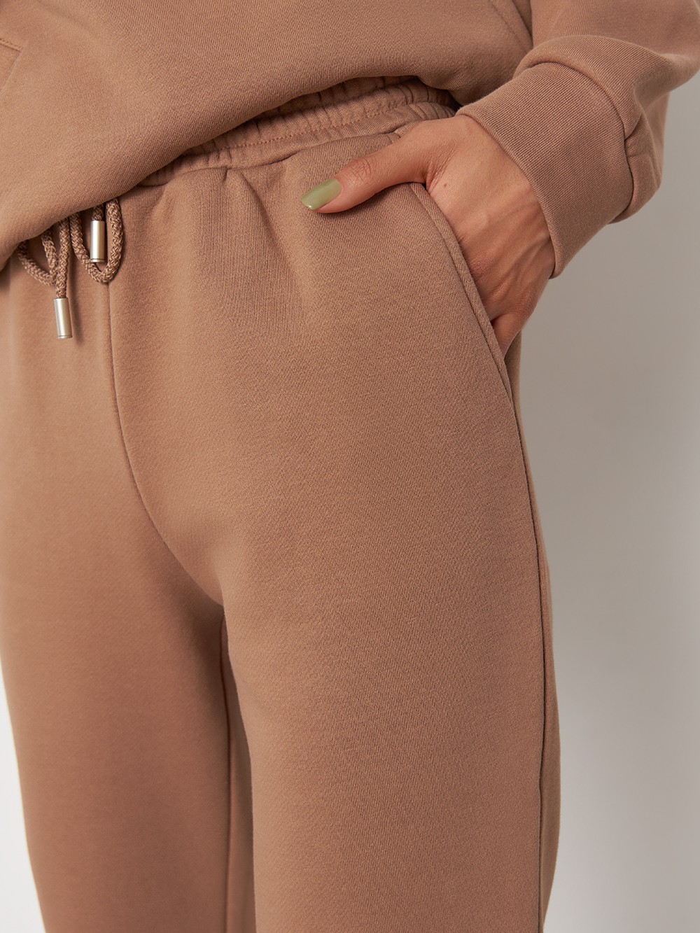 Брюки свободного спортивного силуэта. Модель дополнена манжетами из основной ткани по низу изделия и карманами по боковым швам. На поясе у брюк пояс, регулируемый завязками. Дополните свой образ толстовкой в тон изделия.

На модели размер XS