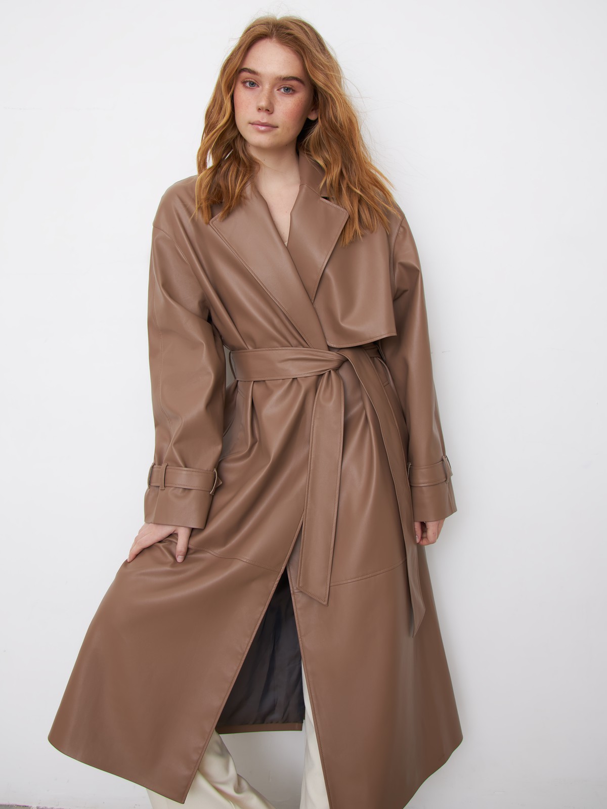 Двубортный плащиз эко-кожи - новая классика современного гардероба. Модель свободной посадки акцентирована отлетными деталями, поясом на талии и скошенными прорезными карманами с широкими листочками.

На модели размер XS/S