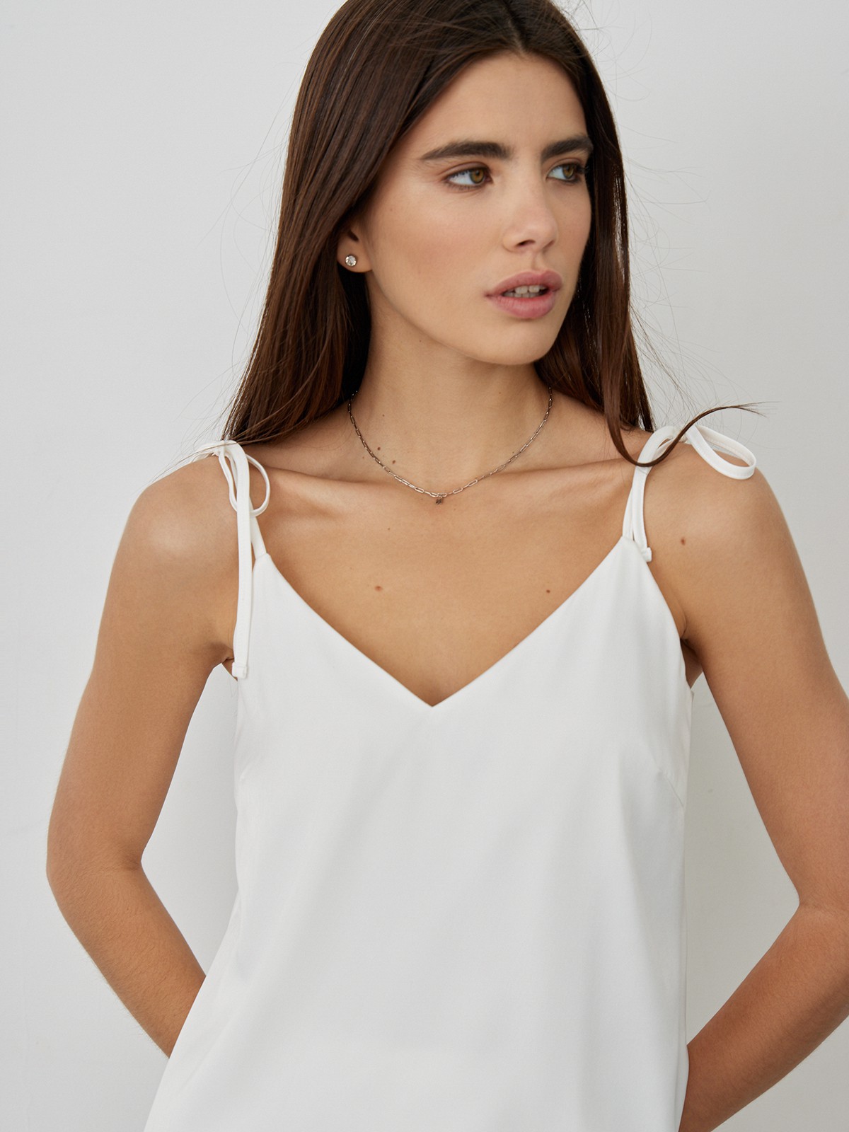 Топ в бельевом стиле оформлен аккуратным V-вырезом и тонкими бретельками на завязках. Универсальный выбор при создании повседневного, офисного и образа для выхода в свет. Сочетайте с юбкой в тон и лаконичными украшениями.

На модели размер XS