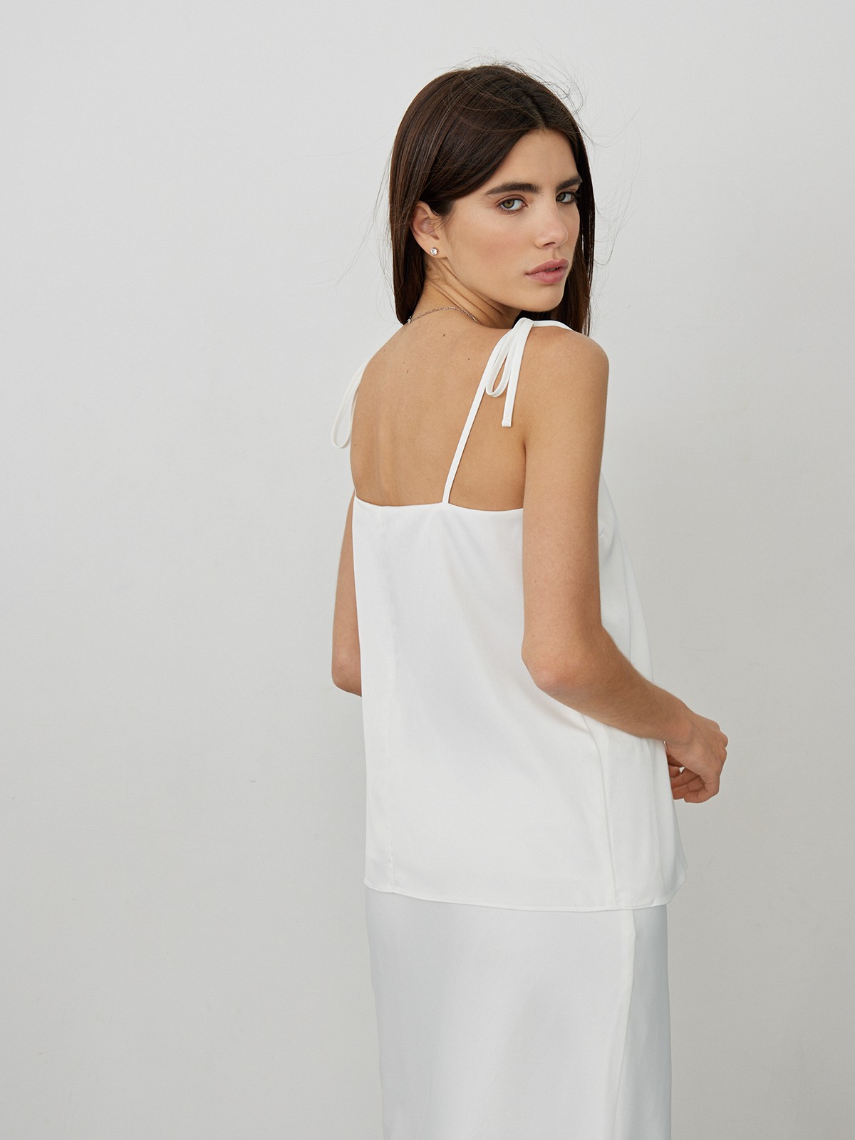 Топ в бельевом стиле оформлен аккуратным V-вырезом и тонкими бретельками на завязках. Универсальный выбор при создании повседневного, офисного и образа для выхода в свет. Сочетайте с юбкой в тон и лаконичными украшениями.

На модели размер XS