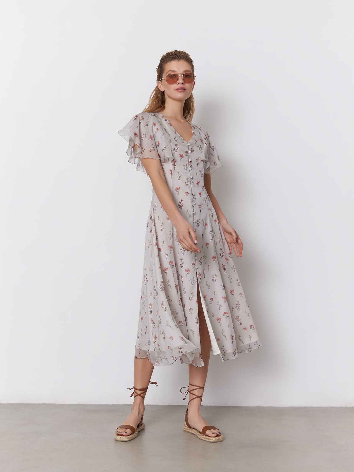 Платье миди из струящегося полупрозрачного шифона с принтом. Многослойные рукава-крылышки вторят сборкам на подоле платья и придают романтичное настроение. Аккуратный V-образный вырез переходит в застежку на обтяжные пуговицы. Идеальный летний силуэт.

На модели размер S