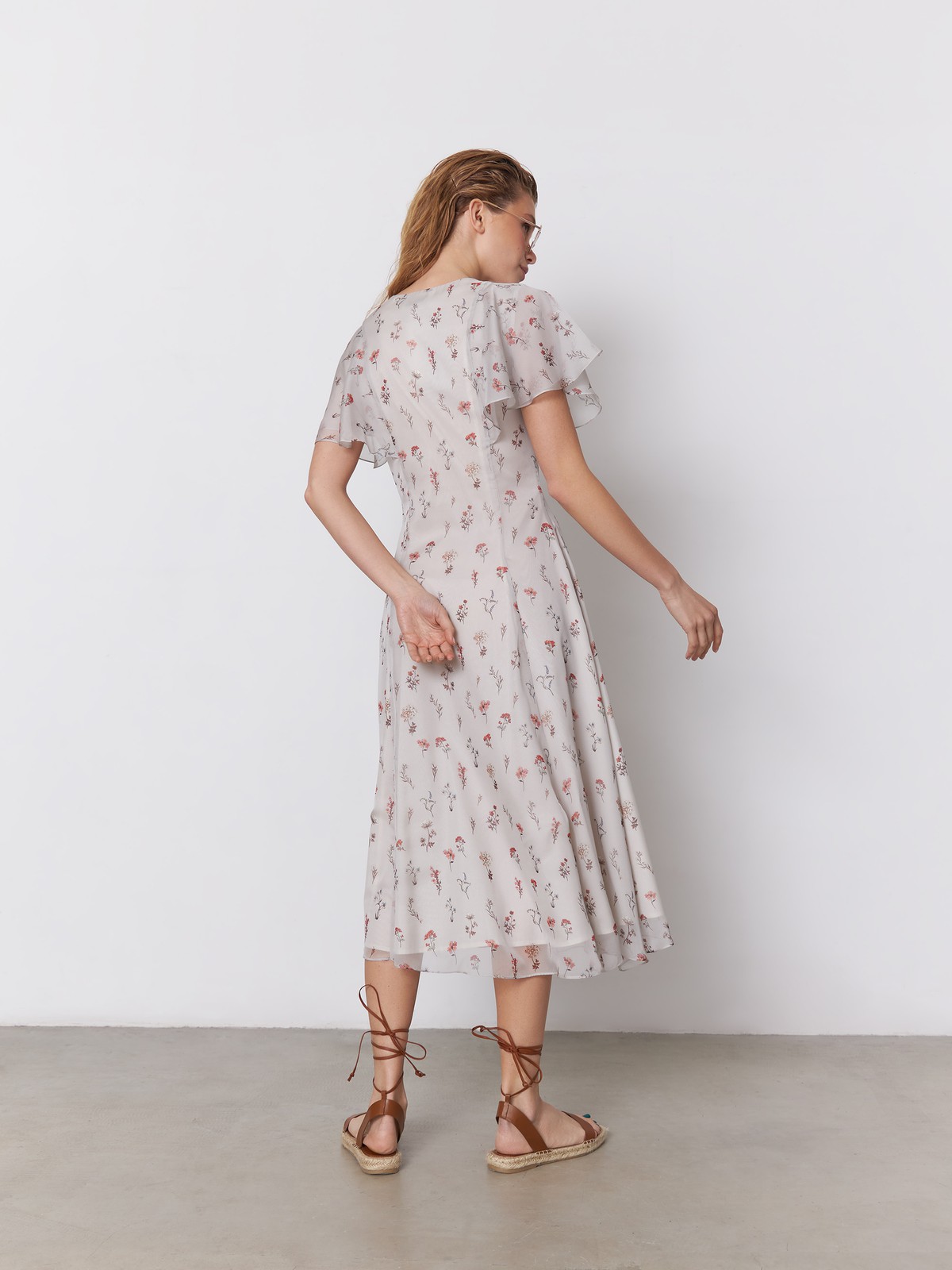 Платье миди из струящегося полупрозрачного шифона с принтом. Многослойные рукава-крылышки вторят сборкам на подоле платья и придают романтичное настроение. Аккуратный V-образный вырез переходит в застежку на обтяжные пуговицы. Идеальный летний силуэт.

На модели размер S