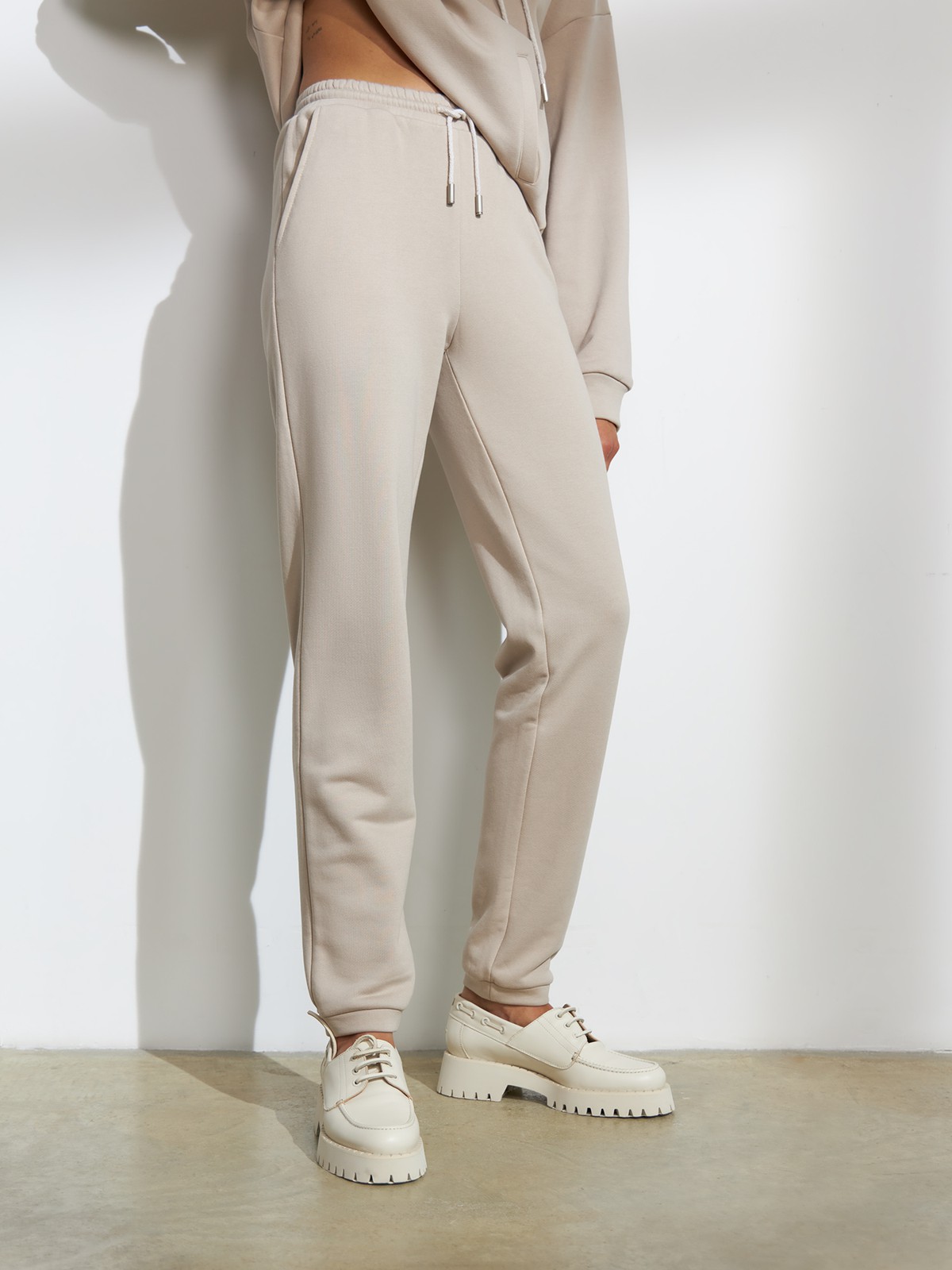 Брюки свободного спортивного силуэта. Модель дополнена манжетами из основной ткани по низу изделия и карманами по боковым швам. На поясе у брюк пояс, регулируемый завязками. Дополните свой образ толстовкой в тон изделия.

На модели размер XS