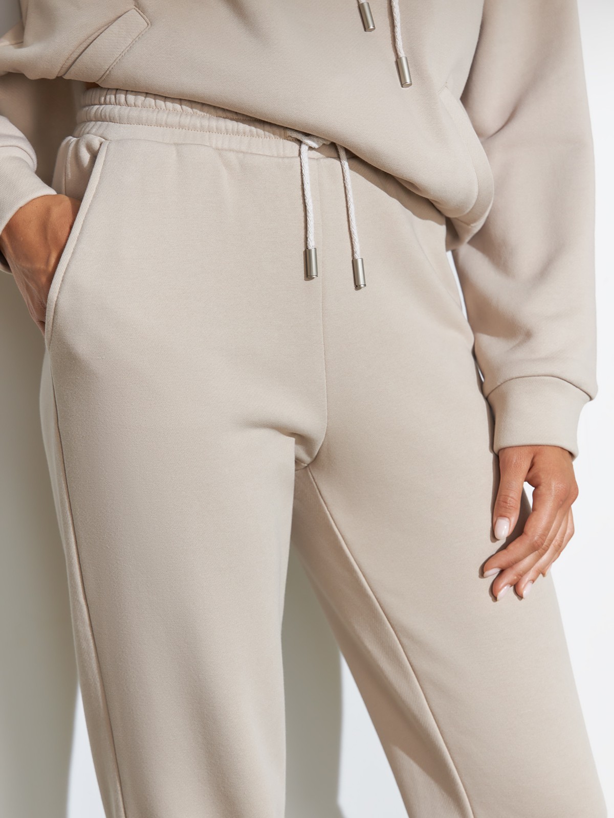 Брюки свободного спортивного силуэта. Модель дополнена манжетами из основной ткани по низу изделия и карманами по боковым швам. На поясе у брюк пояс, регулируемый завязками. Дополните свой образ толстовкой в тон изделия.

На модели размер XS