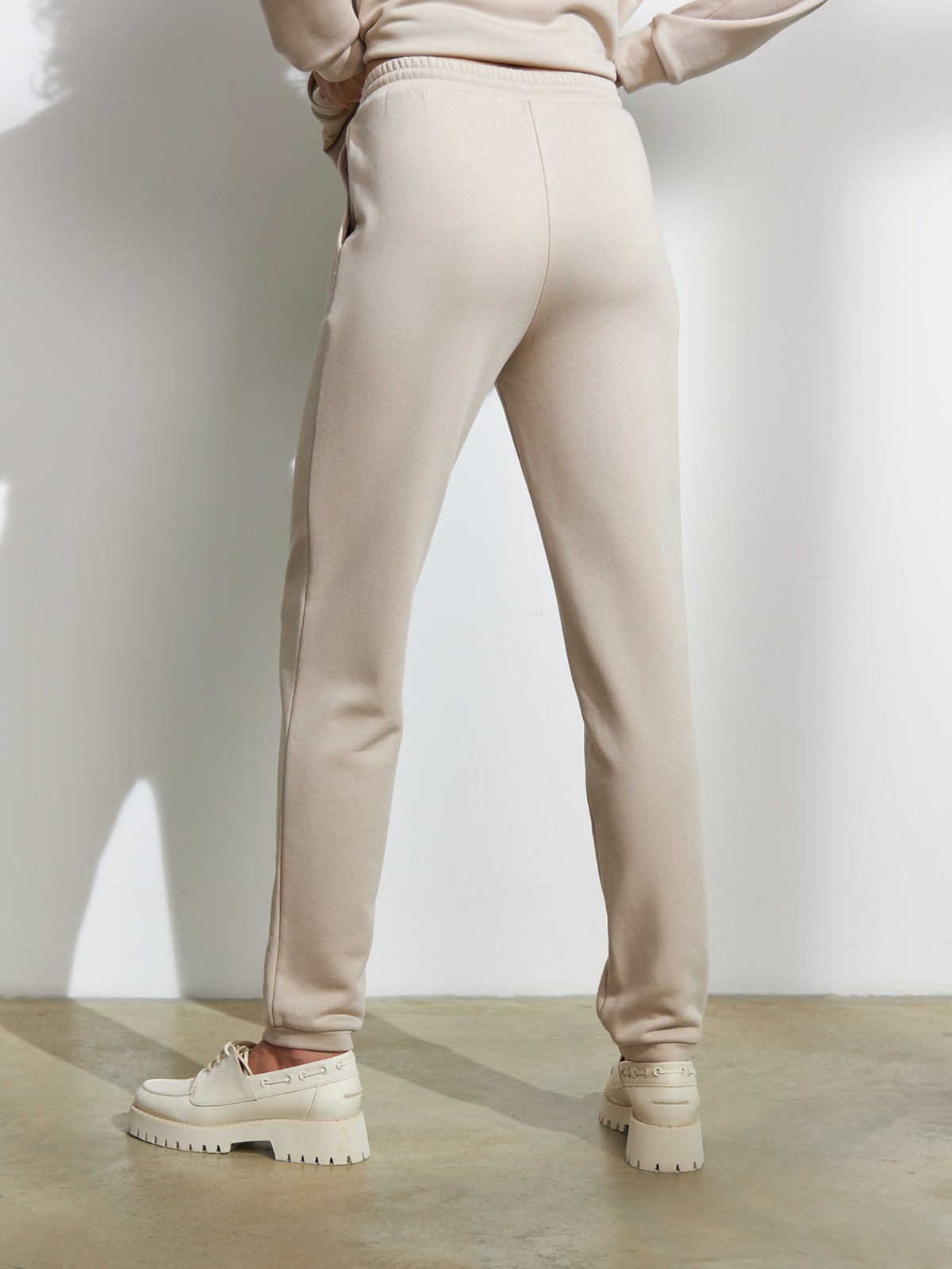 Брюки свободного спортивного силуэта. Модель дополнена манжетами из основной ткани по низу изделия и карманами по боковым швам. На поясе у брюк пояс, регулируемый завязками. Дополните свой образ толстовкой в тон изделия.

На модели размер XS