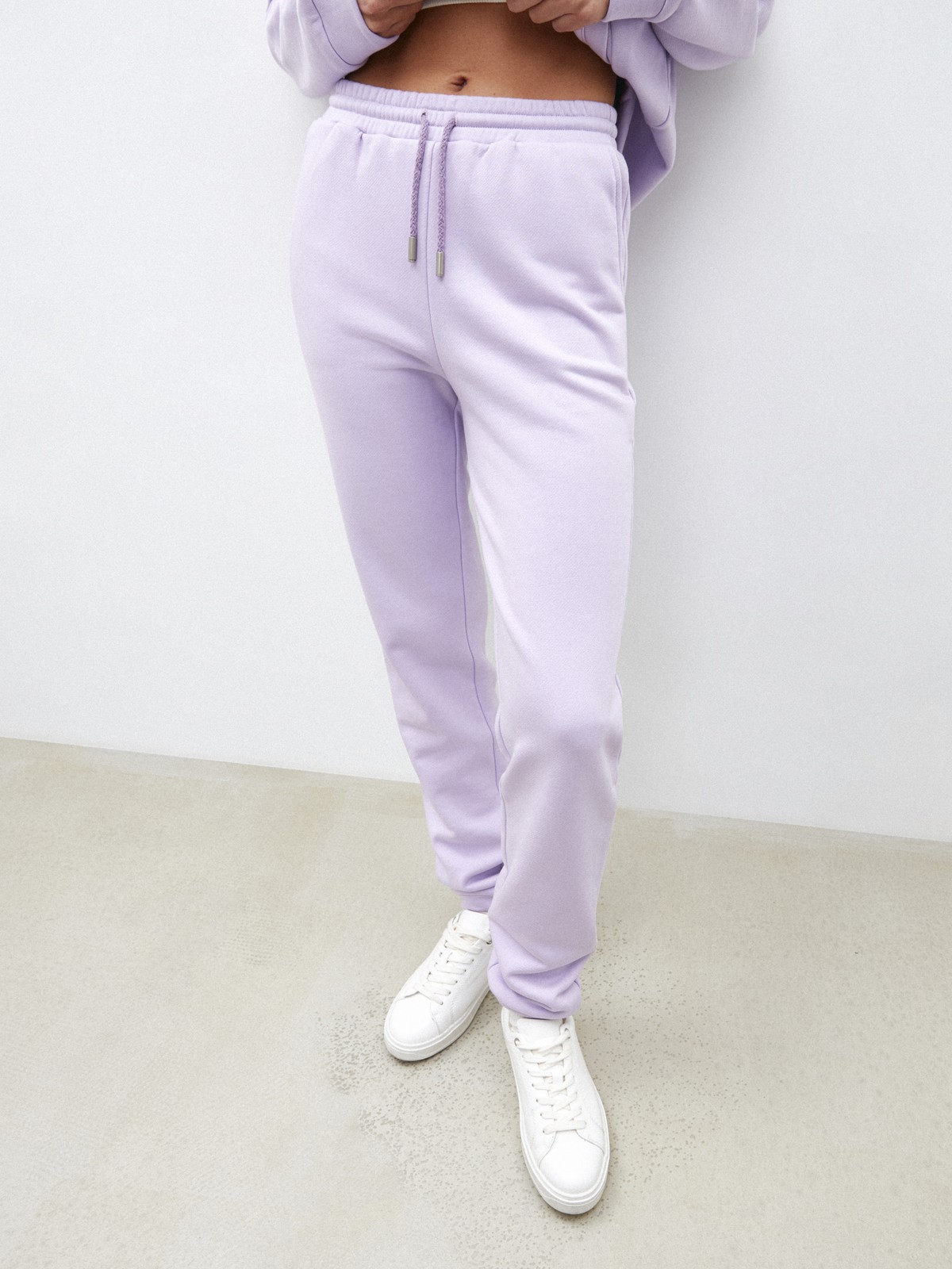 Брюки свободного спортивного силуэта. Модель дополнена манжетами из основной ткани по низу изделия и карманами по боковым швам. На поясе у брюк пояс, регулируемый завязками. Дополните свой образ толстовкой в тон изделия.

На модели размер XS