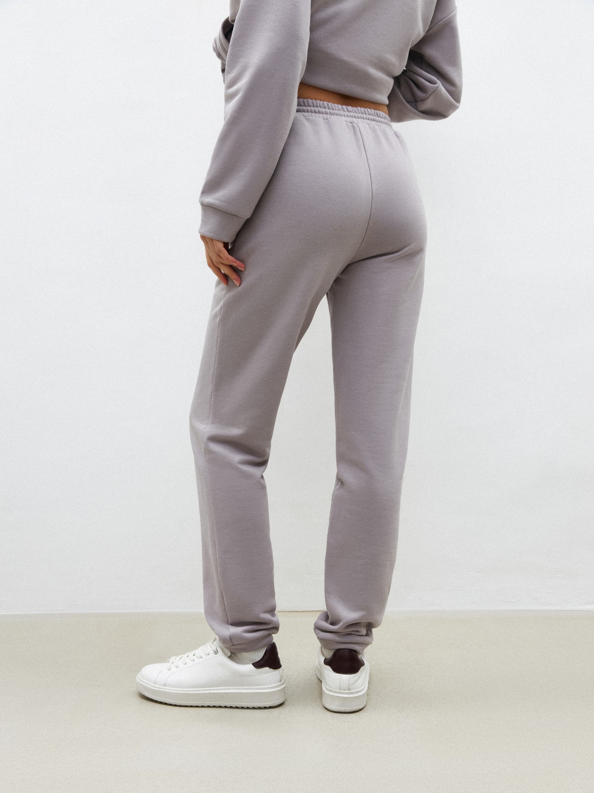 Брюки свободного спортивного силуэта. Модель дополнена манжетами из основной ткани по низу изделия и карманами по боковым швам. На поясе у брюк пояс, регулируемый завязками. Дополните свой образ толстовкой в тон изделия.

На модели размер XS