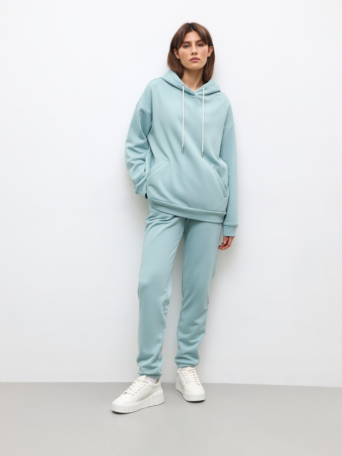 Брюки свободного спортивного силуэта. Модель дополнена манжетами из основной ткани по низу изделия и карманами по боковым швам. На поясе у брюк пояс, регулируемый завязками. Дополните свой образ толстовкой в тон изделия.

На модели размер XS