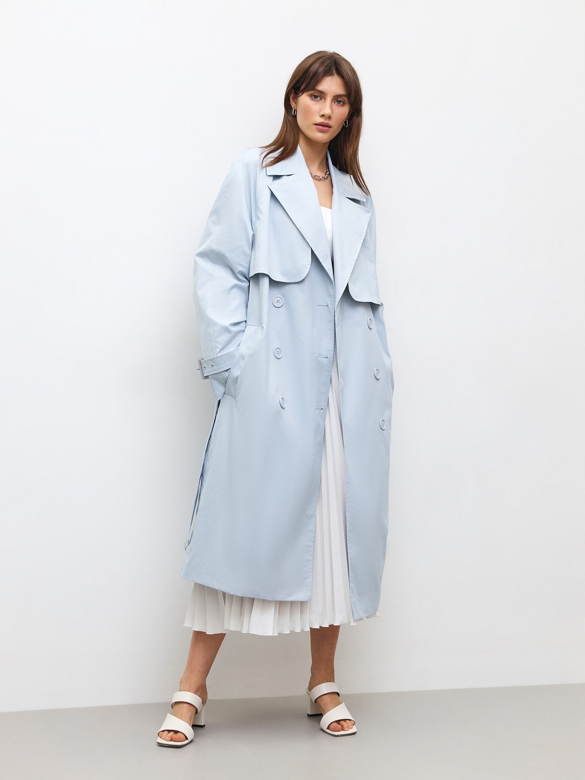 Тренч, цвет: серо-голубой Allweneed Плащдвубортного кроя с застежкой на крупные однотонные пуговицы. Отлетная кокетка, А-силуэт и длинный пояс на талии добавляют образу легкости, а цветовая гамма создает поистине весеннее настроение.