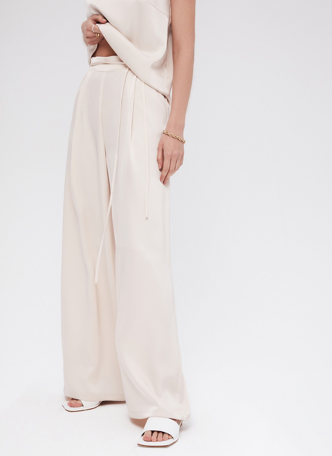 Брюки палаццо, цвет: бежевый Allweneed
Легкие брюки свободного кроя из ткани атласного переплетения. Ткань струится и переливается при ходьбе, но неприхотлива в уходе. Широкий пояс с резинкой, декоративный шнурок на поясе, глубокие складки на передней части брюк. Удобные карманы. Вы можете добавить по желанию изящные босоножки или удобные кеды, футболку oversize или топ с открытой спиной. Можно составить комплект с рубашкой и топом из нашей коллекции.
На модели размер XS