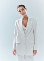 Объемный жакет "с мужского плеча", цвет: белый Allweneed Жакет с объёмной линией плеча. Принадлежит к костюмной группе, ставшей основной в нашей новогодней капсуле. Шлица на спинке для декора и комфорта. Два кармана и пуговицы на рукаве. Мы создали слегка удлинённую модель свободного кроя, которая подходит девушкам с разным ростом. Приятная костюмная ткань имеет деликатный отблеск и хорошо держит форму. В праздник наденьте его с брюками из коллекции или с женственным платьем-комбинацией из тонкой вискозы. Представлен в трёх цветах: сиреневый рассказывает о тихом утре 1 января, красный апельсин символизирует мандарины и гирлянды, а белый это чистый зимний снег.