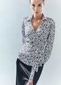 Блуза с запахом, цвет: Бело-черный Allweneed Блуза с запахом и длинным рукавом. Пояс из собственной ткани, чтобы затянуть модель и подчеркнуть талию. Благодаря запаху создаётся красивая зона декольте. Одна из самых адаптивных к будням составляющих новогодней капсулы. Изделие равно хорошо дополнит утончённый и романтичный и дерзкий сексуальный образы из-за принта, отдалённо напоминающего анималистичный. Вы можете сочетать блузу с любимыми брюками и летящими юбками или как мы с атласной юбкой из праздничной коллекции.