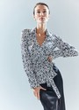 Блуза с запахом, цвет: Бело-черный Allweneed Блуза с запахом и длинным рукавом. Пояс из собственной ткани, чтобы затянуть модель и подчеркнуть талию. Благодаря запаху создаётся красивая зона декольте. Одна из самых адаптивных к будням составляющих новогодней капсулы. Изделие равно хорошо дополнит утончённый и романтичный и дерзкий сексуальный образы из-за принта, отдалённо напоминающего анималистичный. Вы можете сочетать блузу с любимыми брюками и летящими юбками или как мы с атласной юбкой из праздничной коллекции.