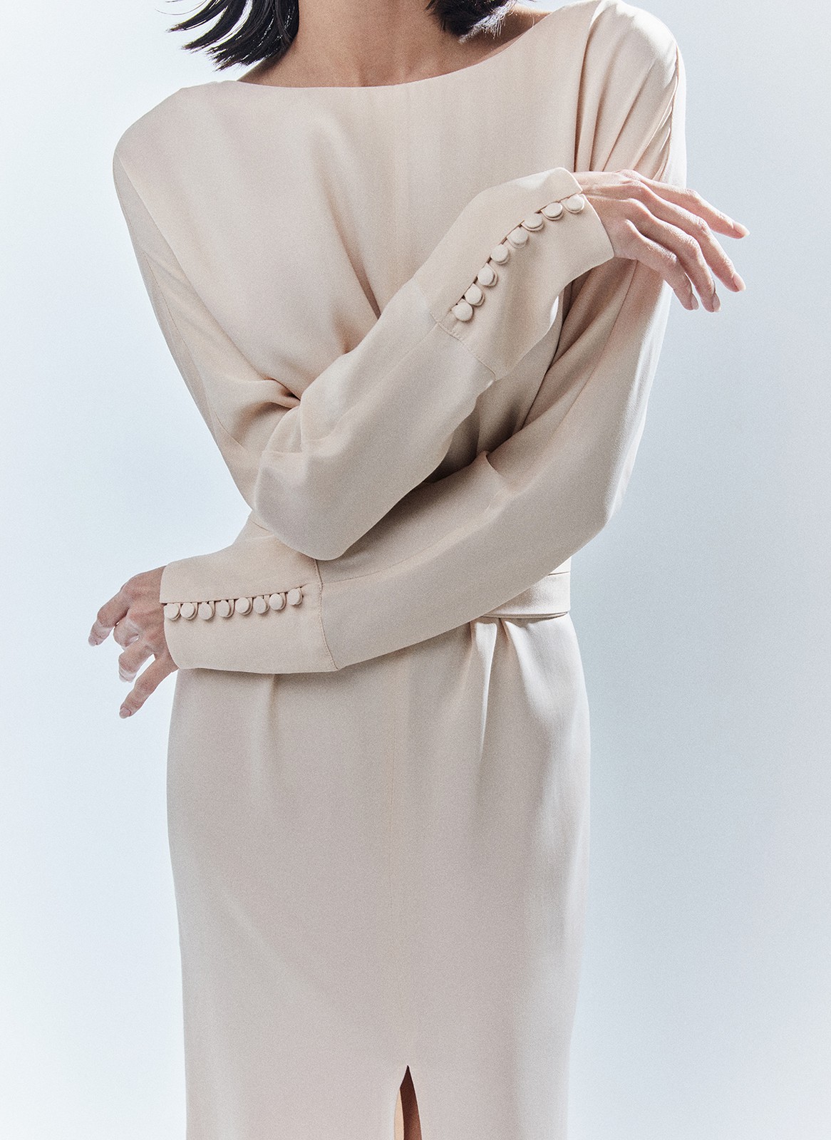 Платье длины миди с разрезом спереди. Свободный крой, деликатное сияние и струящийся материал. Акцентная деталь длинные манжеты с рядом декоративных пуговиц. На спине есть красивый V-образный вырез. Мы создали модель для праздничных моментов, но её легко добавить в гардероб на каждый день благодаря длинному рукаву и сдержанной зоне декольте. Носите для ощущения свободы в движениях или подчеркните талию широким поясом-кушаком ещё одним связующим звеном коллекции. Этот элемент костюма с восточными корнями в старину использовали и для хранения мелочей, и для утепления. Мы же оставили ему декоративное назначение.

