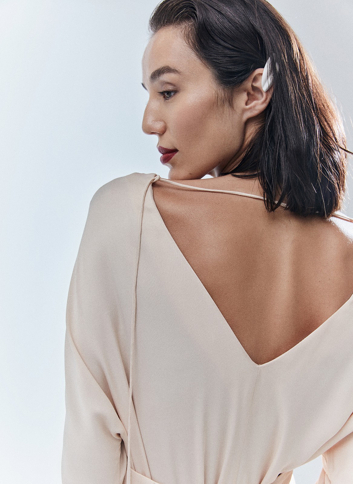 Платье длины миди с разрезом спереди. Свободный крой, деликатное сияние и струящийся материал. Акцентная деталь длинные манжеты с рядом декоративных пуговиц. На спине есть красивый V-образный вырез. Мы создали модель для праздничных моментов, но её легко добавить в гардероб на каждый день благодаря длинному рукаву и сдержанной зоне декольте. Носите для ощущения свободы в движениях или подчеркните талию широким поясом-кушаком ещё одним связующим звеном коллекции. Этот элемент костюма с восточными корнями в старину использовали и для хранения мелочей, и для утепления. Мы же оставили ему декоративное назначение.

