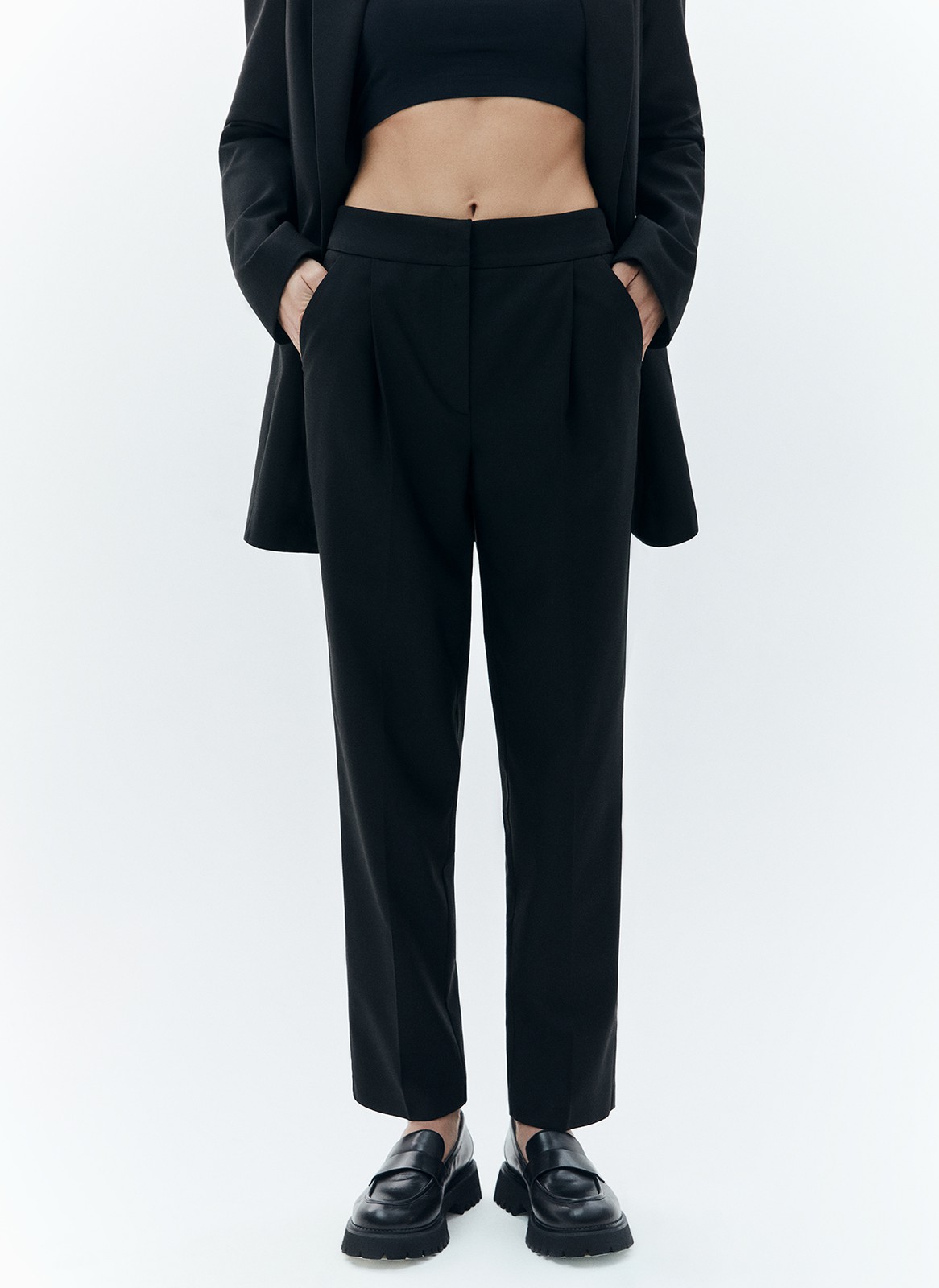 Брюки укороченные, зауженные к низу, цвет: Черный Allweneed Зауженные брюки на средней посадке из костюмной ткани. Модель на складке и со стрелкой. Ткань хорошо держит форму, поэтому изделие долго сохраняет свой первоначальный вид. Два кармана с отрезным бочком и скрытая застёжка на молнию. Мы любим такую длину брюк, которая смотрится оптимально с обувью на каблуке и без него. Идеально, чтобы создать образ деловой леди с жакетом.
