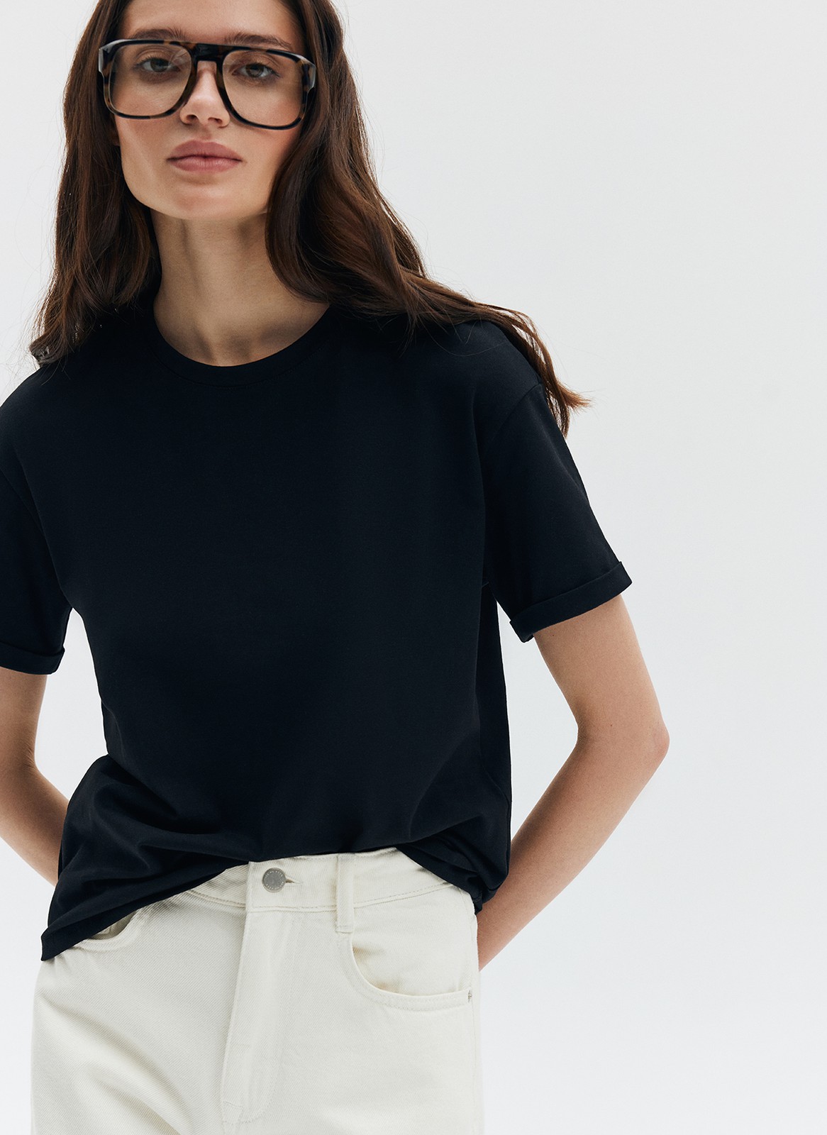 Футболка из эластичного, мягкого хлопка. Базовая модель свободного кроя со спущенным плечом. Благодаря материалу в футболке комфортно целый день идеально для жаркого времени года. Носите с джинсами, юбками и брюками.