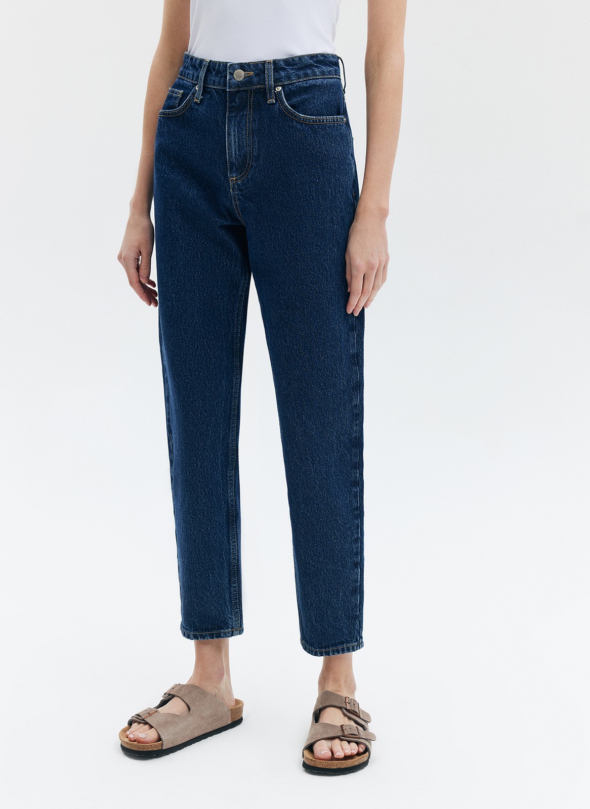 Джинсы Mom fit формируют красивую линию бедра. Слегка свободные, зауженные книзу. Укороченная модель подчеркивает красоту щиколоток. Выполнены из премиального 100% хлопкового денима с авторской варкой и брендированной фурнитурой.