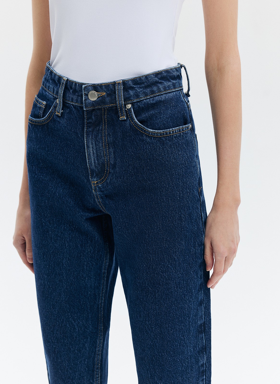 Джинсы Mom fit формируют красивую линию бедра. Слегка свободные, зауженные книзу. Укороченная модель подчеркивает красоту щиколоток. Выполнены из премиального 100% хлопкового денима с авторской варкой и брендированной фурнитурой.